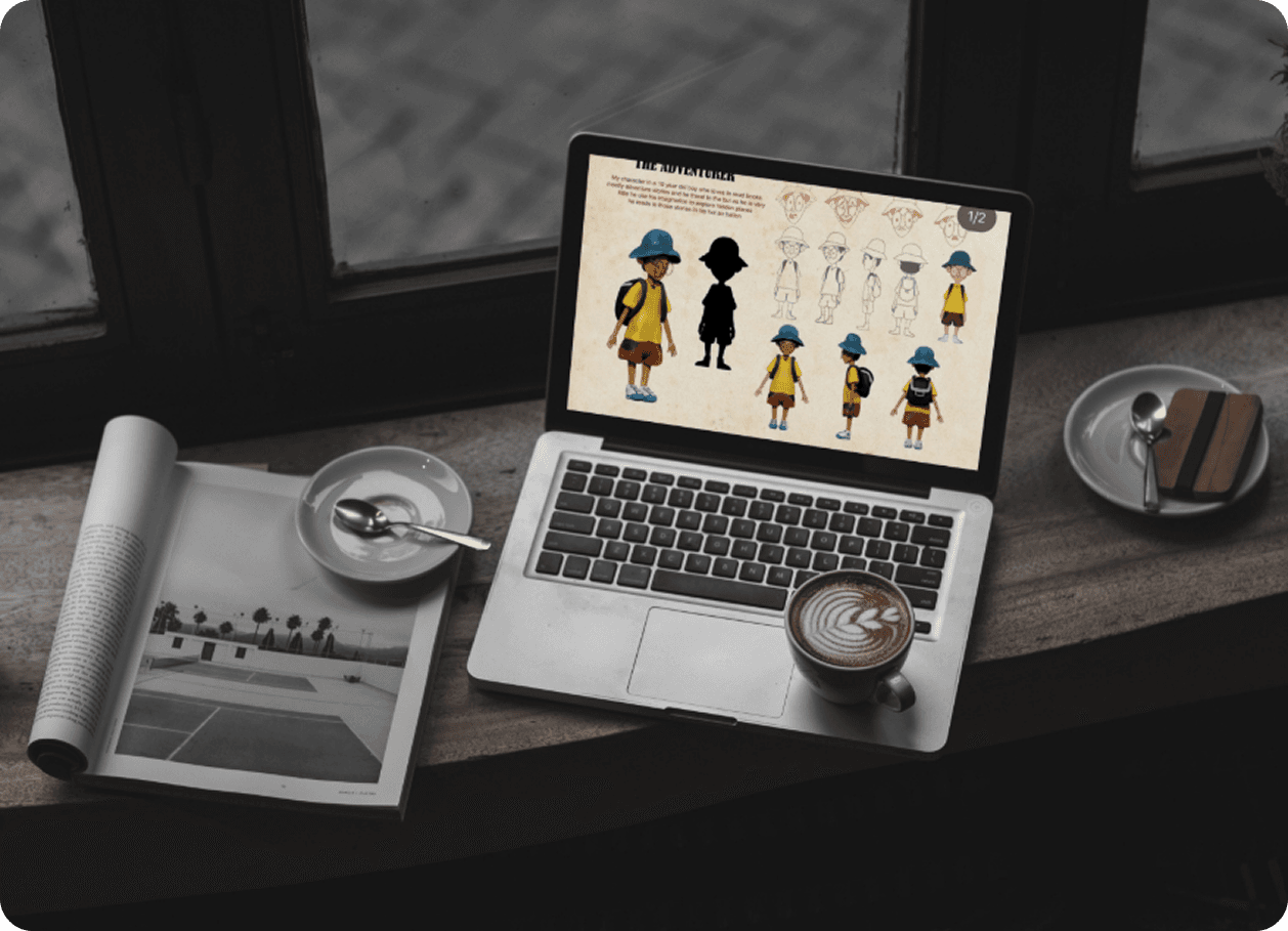 Character concept sheet on laptop beside coffee and magazine